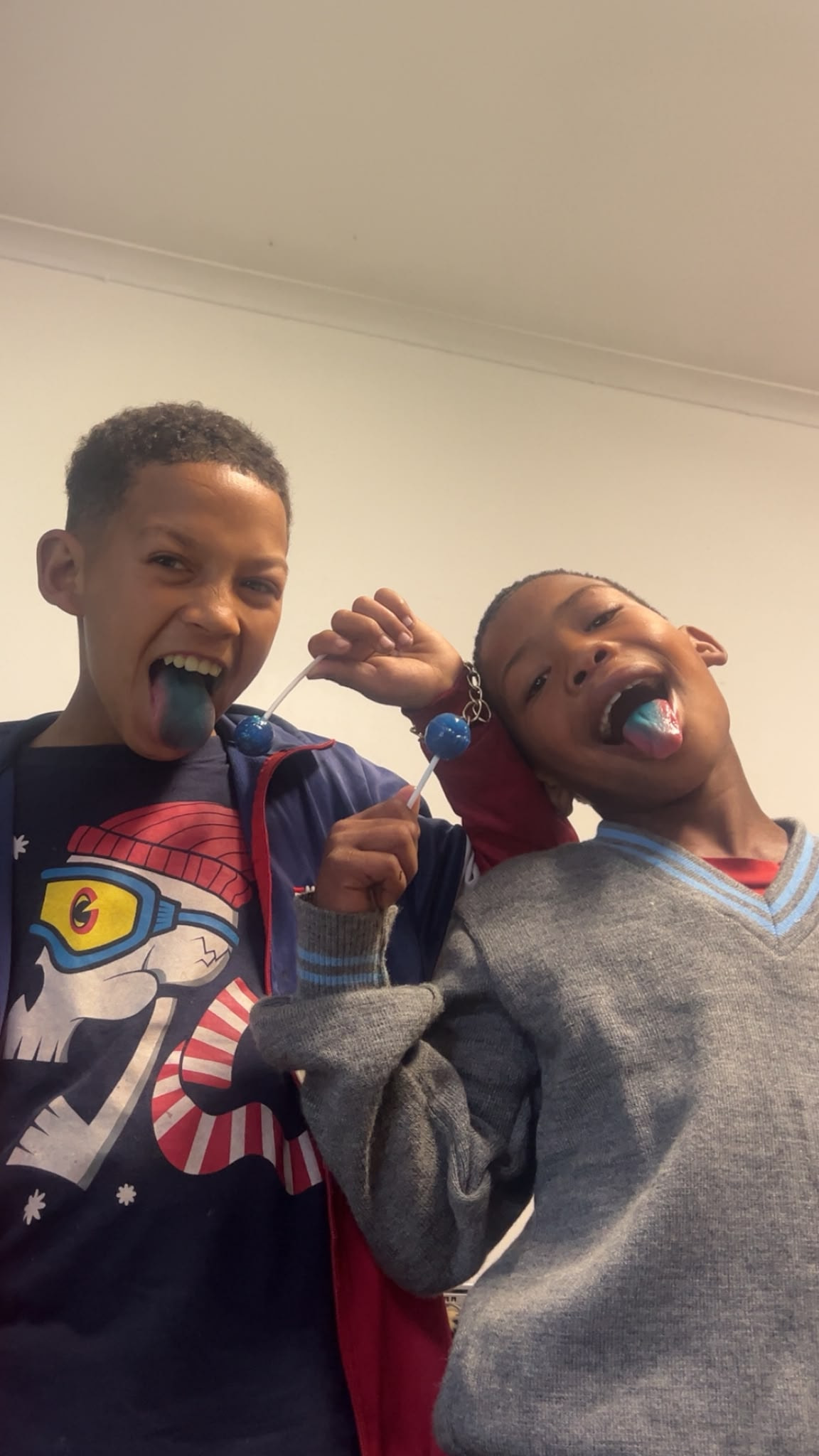 Two boys showing off blue tongues from their sweets