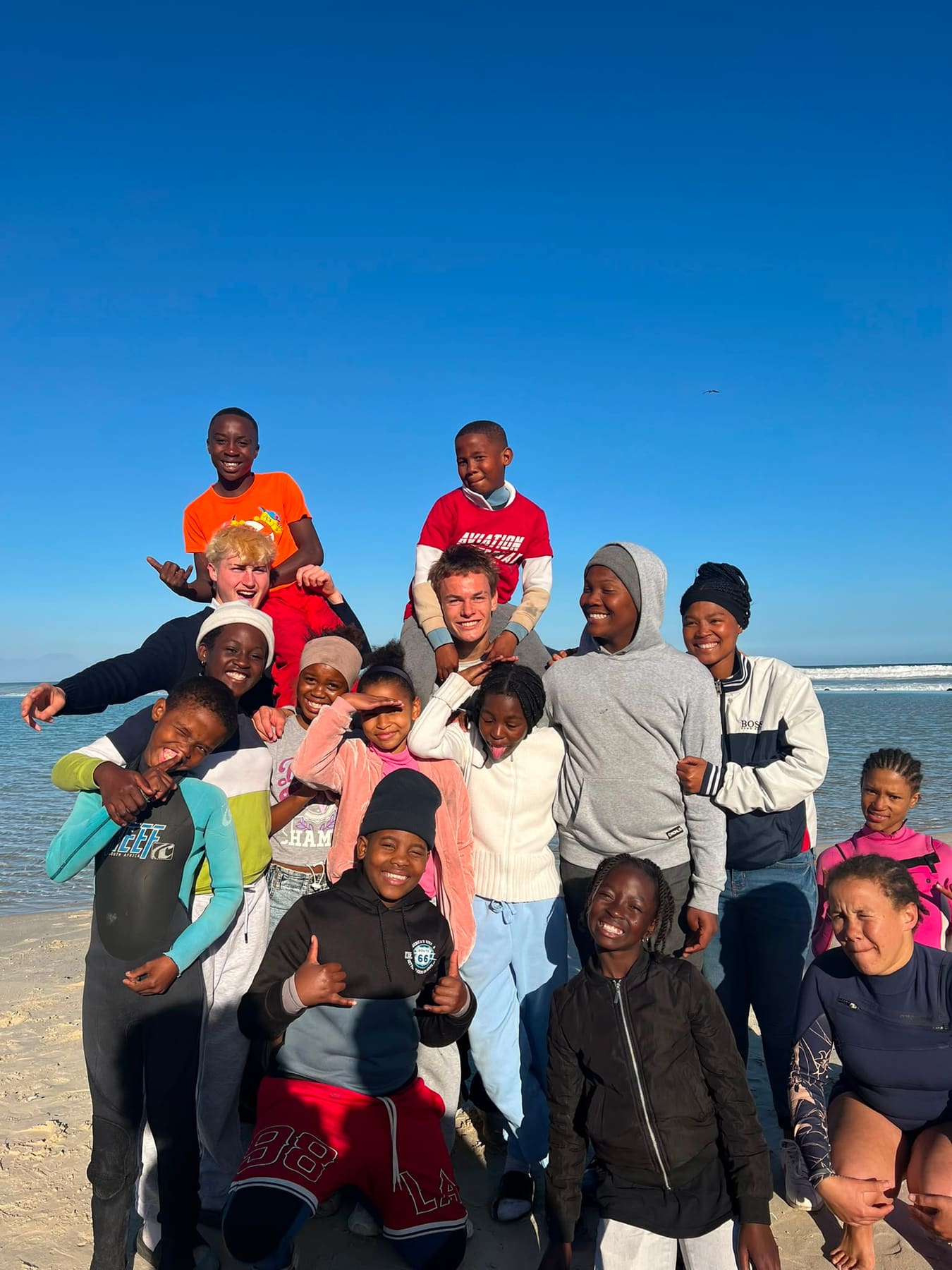 Volunteers and children on the beach with the tide behind
