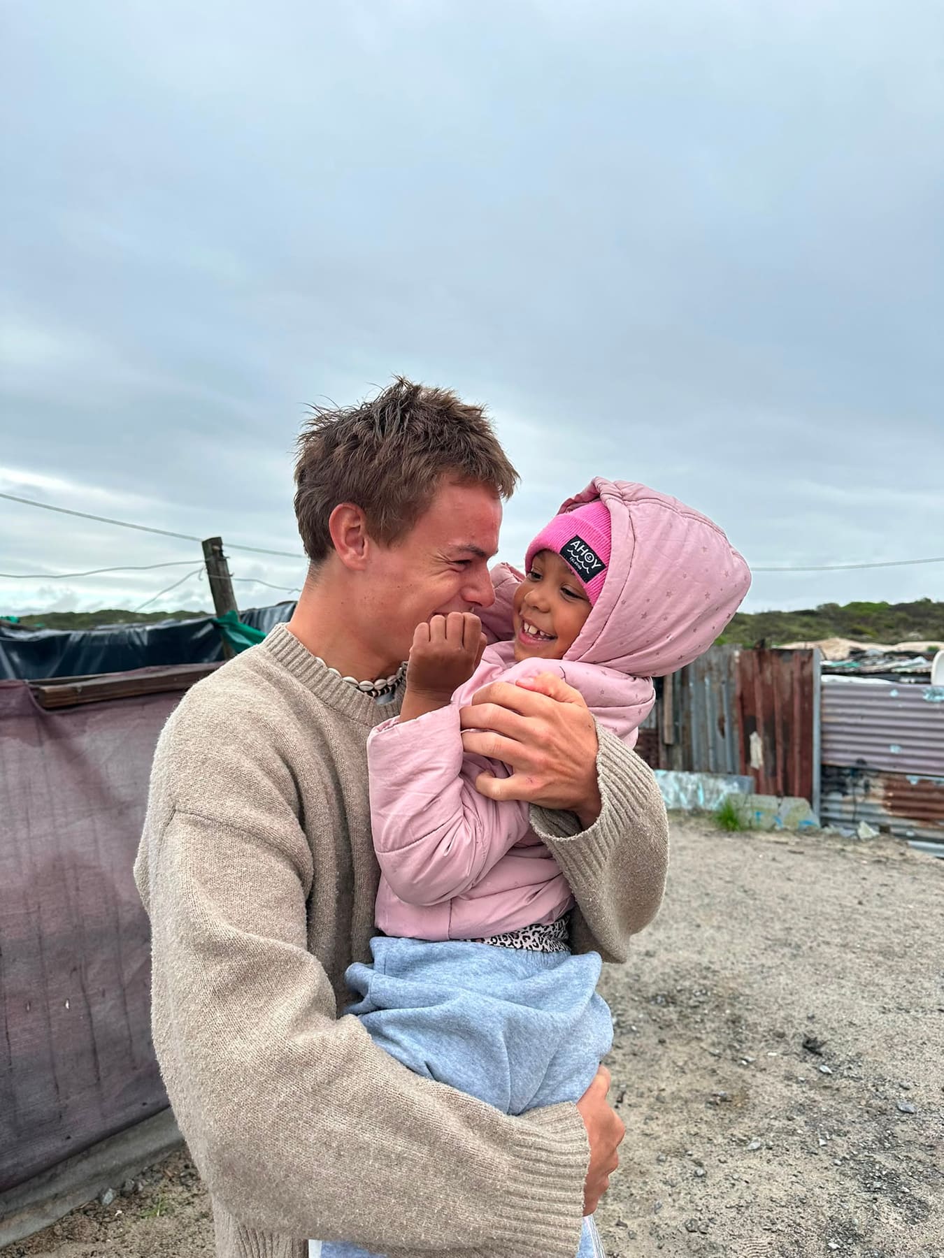 A volunteer holding a young child in a pink hoodie
