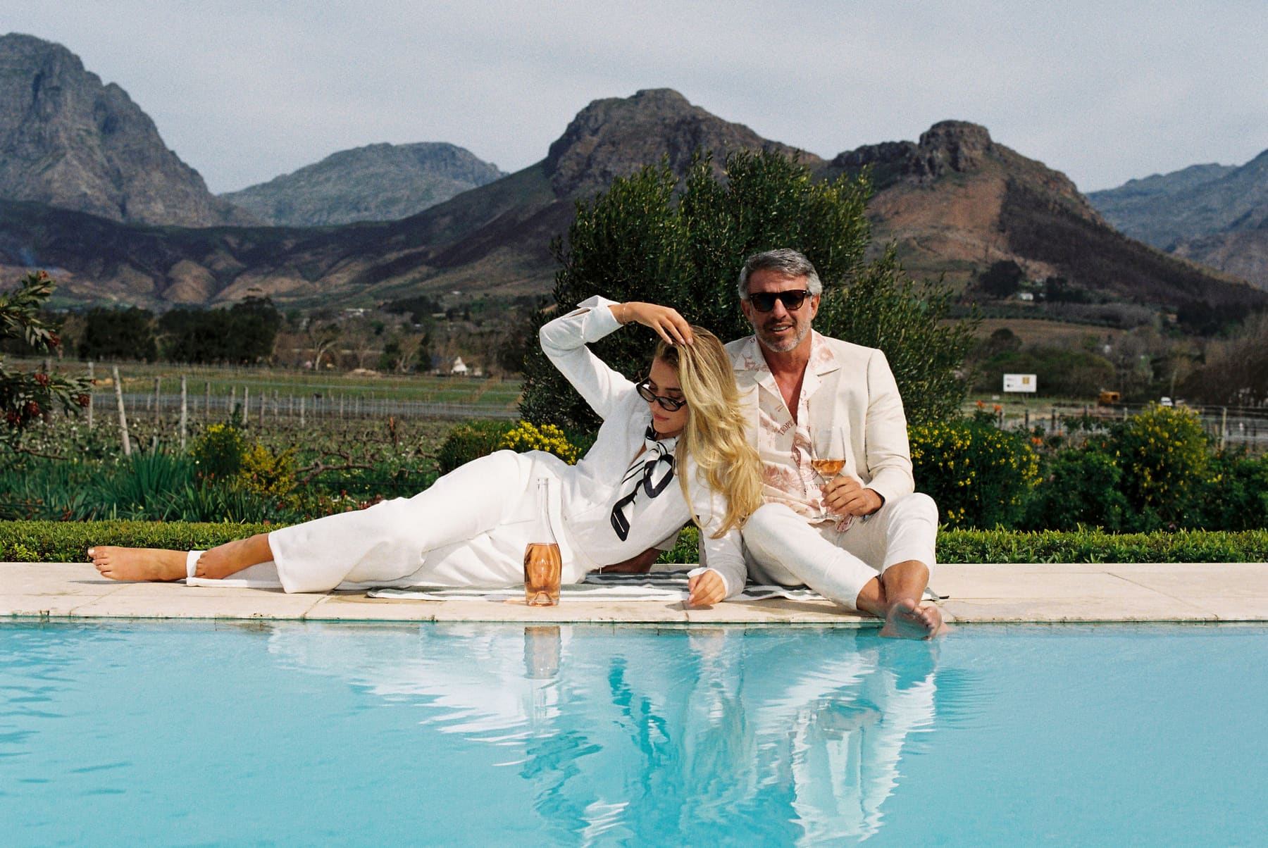 A couple beside an infinity pool with the Franschhoek mountains behind